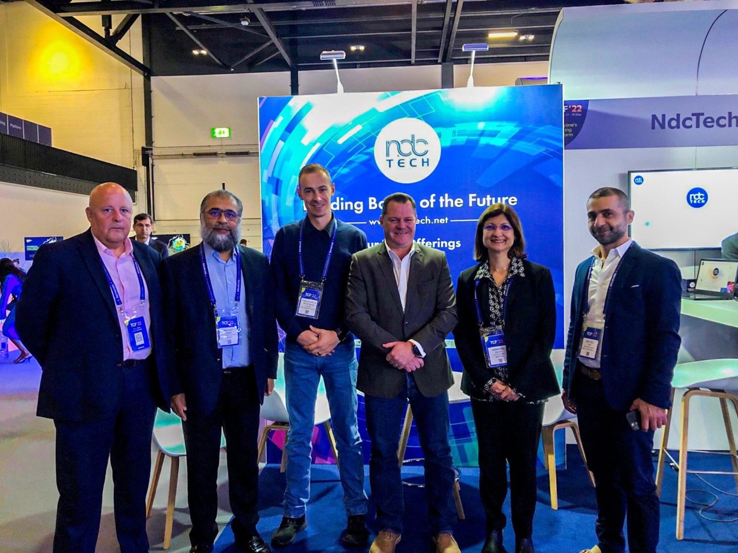A group of people standing in front of a sign
Description automatically generated